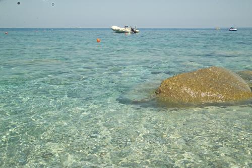 a rock in the water with a boat in the background at Villaggio Hotel Lido San Giuseppe in Briatico