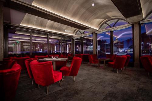 a restaurant with red chairs and a table and windows at Hanul Bran in Bran