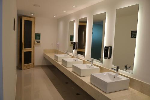 Baño con 4 lavabos y una fila de espejos en Solanas Green Park Spa & Resort en Punta del Este