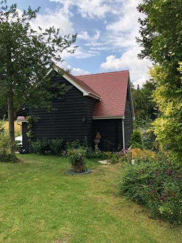 a black house with a red roof and a yard at Ivy Todd cottage in Debden