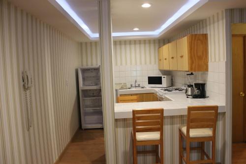 eine Küche mit einer Theke mit Stühlen und einem Kühlschrank in der Unterkunft Hotel & Suites Victoria in San Luis Potosí
