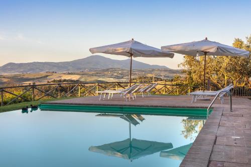 a pool with two umbrellas and chairs and tables at Cosona in Pienza