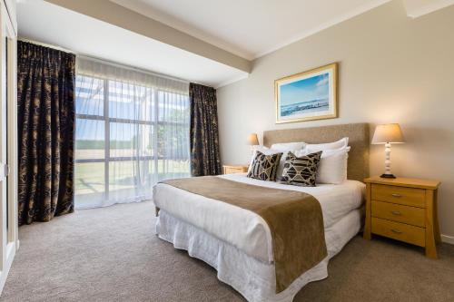 a bedroom with a large bed and a large window at Mangapapa Hotel in Havelock North