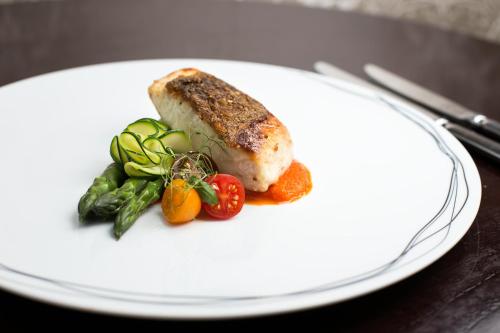 a white plate with a piece of meat and vegetables at Mangapapa Hotel in Havelock North