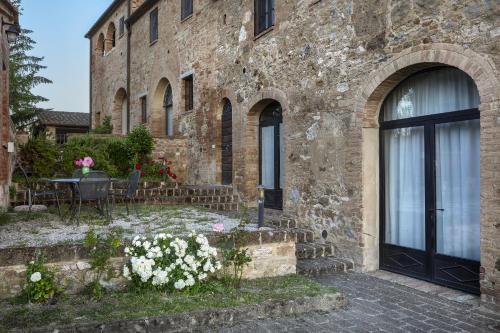a stone building with a door and a table with flowers at Cosona in Pienza
