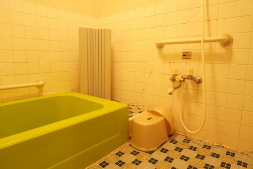 a bathroom with a green tub and a toilet at Villa alive in Takekara