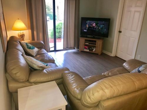 a living room with a leather couch and a flat screen tv at St. Augustine Ocean & Racquet Resort in Saint Augustine