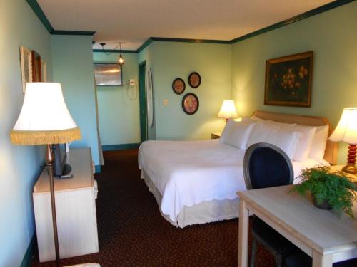 Habitación de hotel con cama y mesa con lámpara en Victorian Inn en Reno