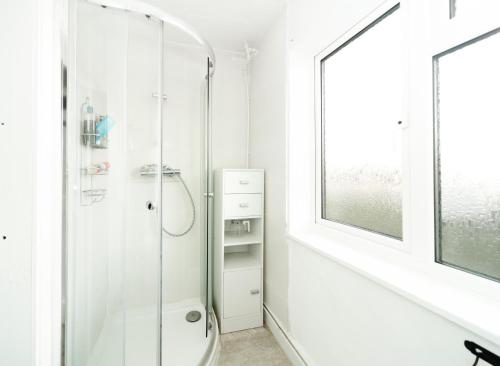 a white bathroom with a shower and a toilet at The Lodge in Walberswick