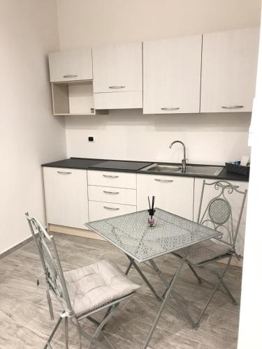 uma cozinha com uma mesa, 2 cadeiras e um lavatório em La Maison - matrimoniale em Stornara
