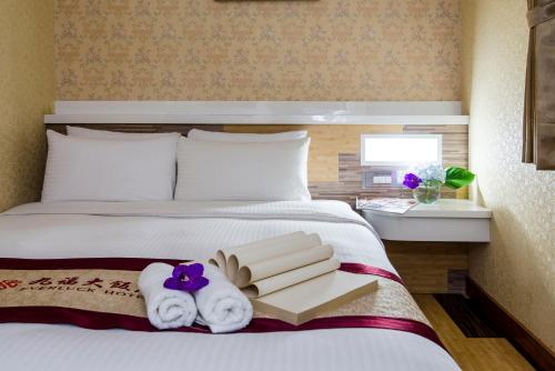 a hotel room with a bed with towels and books at Ever Luck Hotel in Kaohsiung