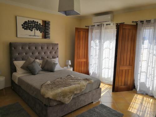 a bedroom with a large bed in a room with windows at Refúgio Do Bem Estar in Cercal