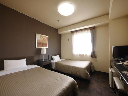 a hotel room with two beds and a window at Hotel Route-Inn Court Yamanashi in Yamanashi