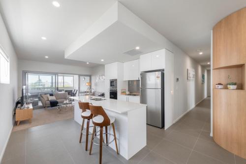 a kitchen and living room with a counter and stools at Astra Apartments Newcastle (Merewether) in Merewether
