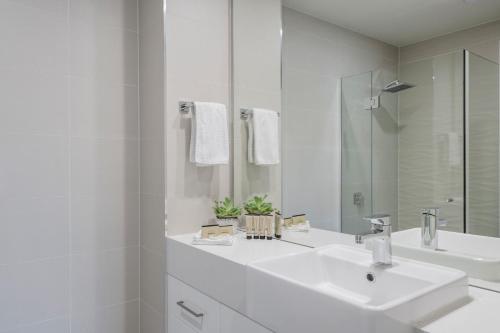 a white bathroom with two sinks and a mirror at Astra Apartments Newcastle (Merewether) in Merewether