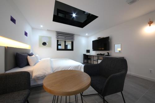 a bedroom with a bed and a table and chairs at 2Night Business Hotel in Jeonju