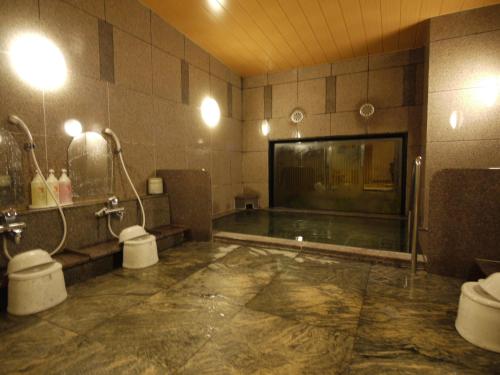 a bathroom with two toilets and a swimming pool at Hotel Route-Inn Hisai Inter in Tsu