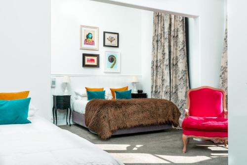 a bedroom with two beds and a red chair at The Duke Of Marlborough in Russell