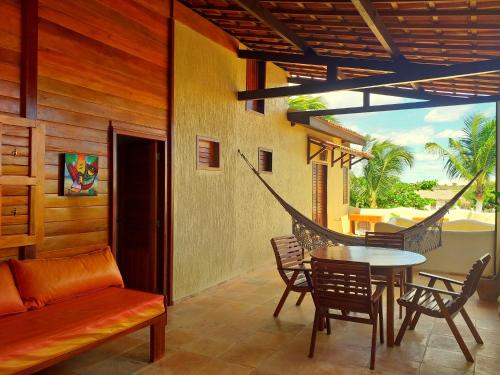 a patio with a table and chairs and a hammock at Pousada Sahara in Jericoacoara