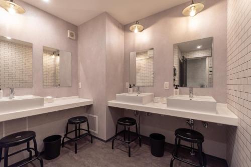 ein Bad mit 3 Waschbecken und 2 Spiegeln in der Unterkunft DOYANEN HOTELs YAMATO in Osaka