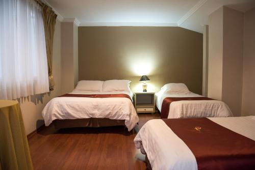 a hotel room with two beds and a window at Hotel La Orquidea in Cuenca