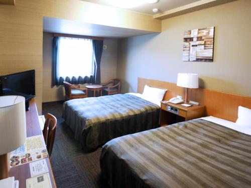 a hotel room with two beds and a flat screen tv at Hotel Route-Inn Suwa Inter in Suwa