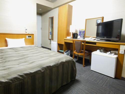 
a hotel room with a bed, desk and television at Hotel Route-Inn Suwa Inter in Suwa
