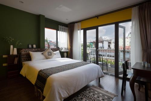a bedroom with a large bed and a large window at Centraltique Downtown - Bespoke Colonial House Near Hoan Kiem Lake in Hanoi