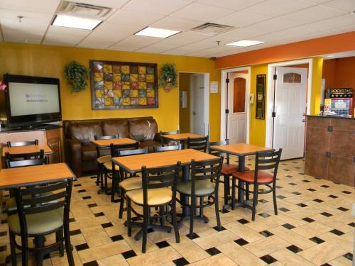 a restaurant with tables and chairs and a television at Days Inn by Wyndham Airport Nashville East in Nashville