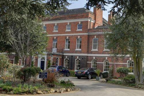a red brick building with cars parked in front of it at Best Western Plus West Retford Hotel in Retford