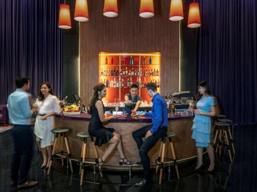 a group of people standing at a bar at Mercure Hai Phong in Hai Phong