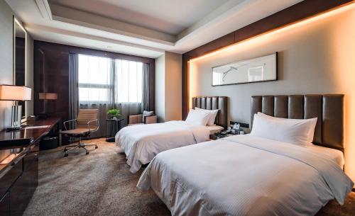 a hotel room with two beds and a desk at Ramada Changzhou North Hotel in Changzhou