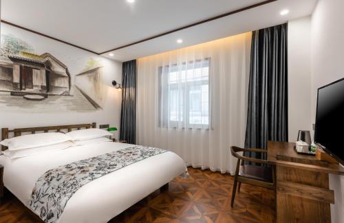 a bedroom with a bed and a desk and a television at Nostalgia Hotel Beijing Prince Gong's Mansion 时光漫步酒店北京恭王府平安里地铁站店 Free fresh ground coffee ,Free laundry service in Beijing