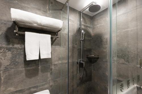 a bathroom with a shower and a toilet and towels at Nostalgia Hotel (Prince Gong Mansion) in Beijing