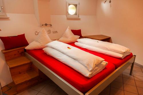 ein Bett mit weißen Kissen und einer roten Decke in der Unterkunft Bergwerksilo Herznach in Herznach