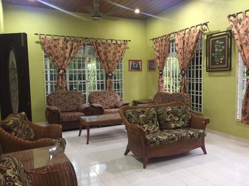 a living room with couches and chairs and windows at Homestay Cikgu Sungai Batu Besi in Bedung