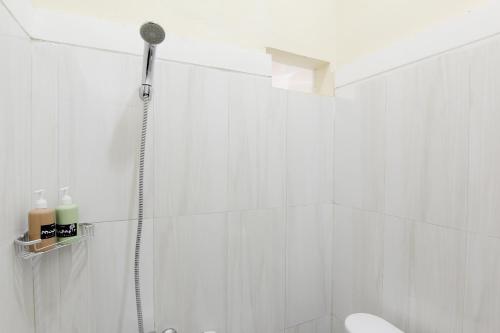 a white bathroom with a shower and a toilet at Musafir Guest House Syariah in Solo
