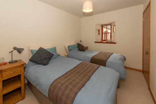 a bedroom with two beds and a table with a lamp at Farmtoun Cottage Apartment in Forfar