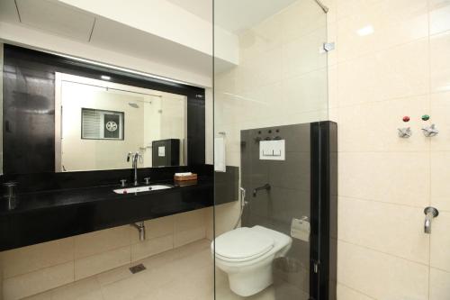 a bathroom with a toilet and a sink and a mirror at Hotel Southern Residency in Kelambākkam