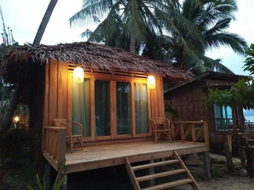 a small hut with chairs and a deck at The Tropical Koh Mook in Koh Mook