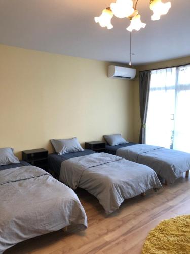 a bedroom with three beds and a chandelier at Amami Weekly House Nico Nico Nazeko-ten in Amami