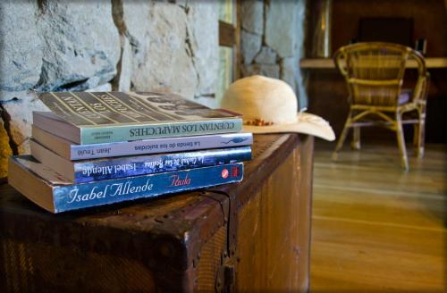 a stack of books sitting on a table with a hat at Luma Casa De Montaña in Villa La Angostura