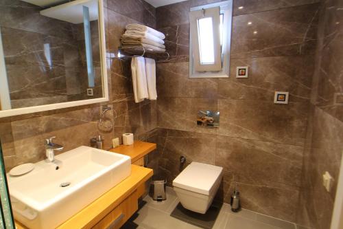 a bathroom with a sink and a toilet and a mirror at The Losh Hotel in Yalıkavak