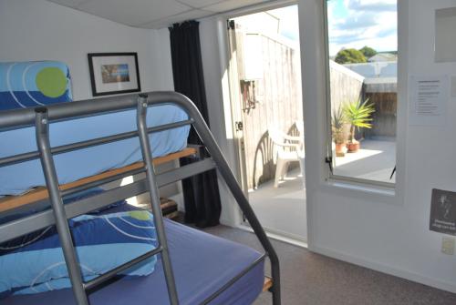 a bunk bed in a room with a balcony at Loft 109 Backpackers Hostel in Tauranga