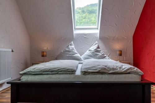 uma cama com duas almofadas num quarto com uma janela em Moselglück em Sankt Aldegund