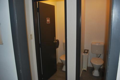 La salle de bains est pourvue de 2 toilettes et d'une porte noire. dans l'établissement Loft 109 Backpackers Hostel, à Tauranga