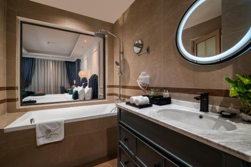 ein Badezimmer mit einer großen Badewanne und einem großen Spiegel in der Unterkunft Dahlia Hotel Hanoi in Hanoi