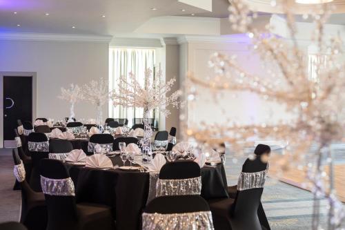 a banquet hall with tables and chairs and lights at Mercure Bedford Centre Hotel in Bedford
