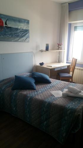 a bedroom with a bed with blue pillows and a desk at Hotel La Bussola in Muggia