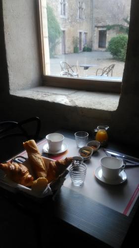 a table with bread and cups and a window at Le Vieux Chateau in Airvault